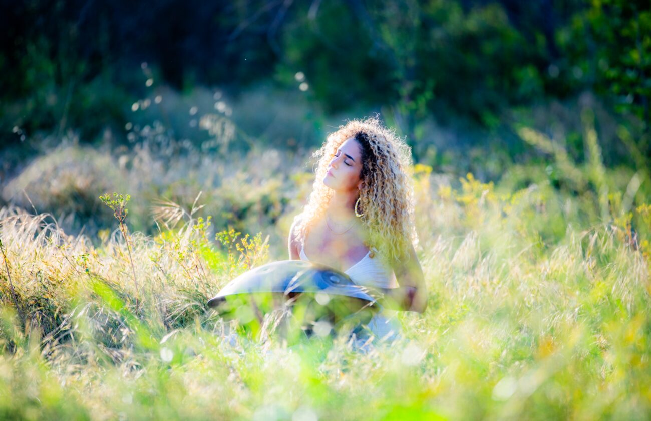 Roni seated in meditation in a green field